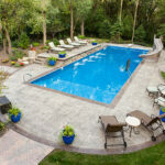 Large swimming pool and patio in a secluded back yard.